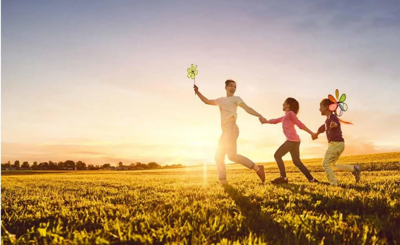 A family running together through a sunlit field.